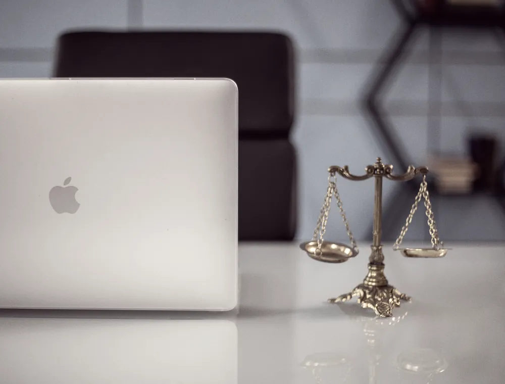 Un bureau avec un ordinateur portable et une balance de la justice