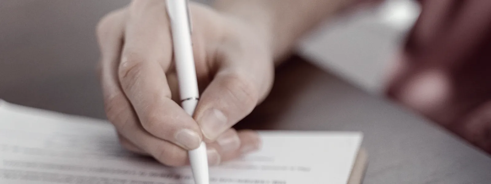 Une main signe un contrat posé sur une table